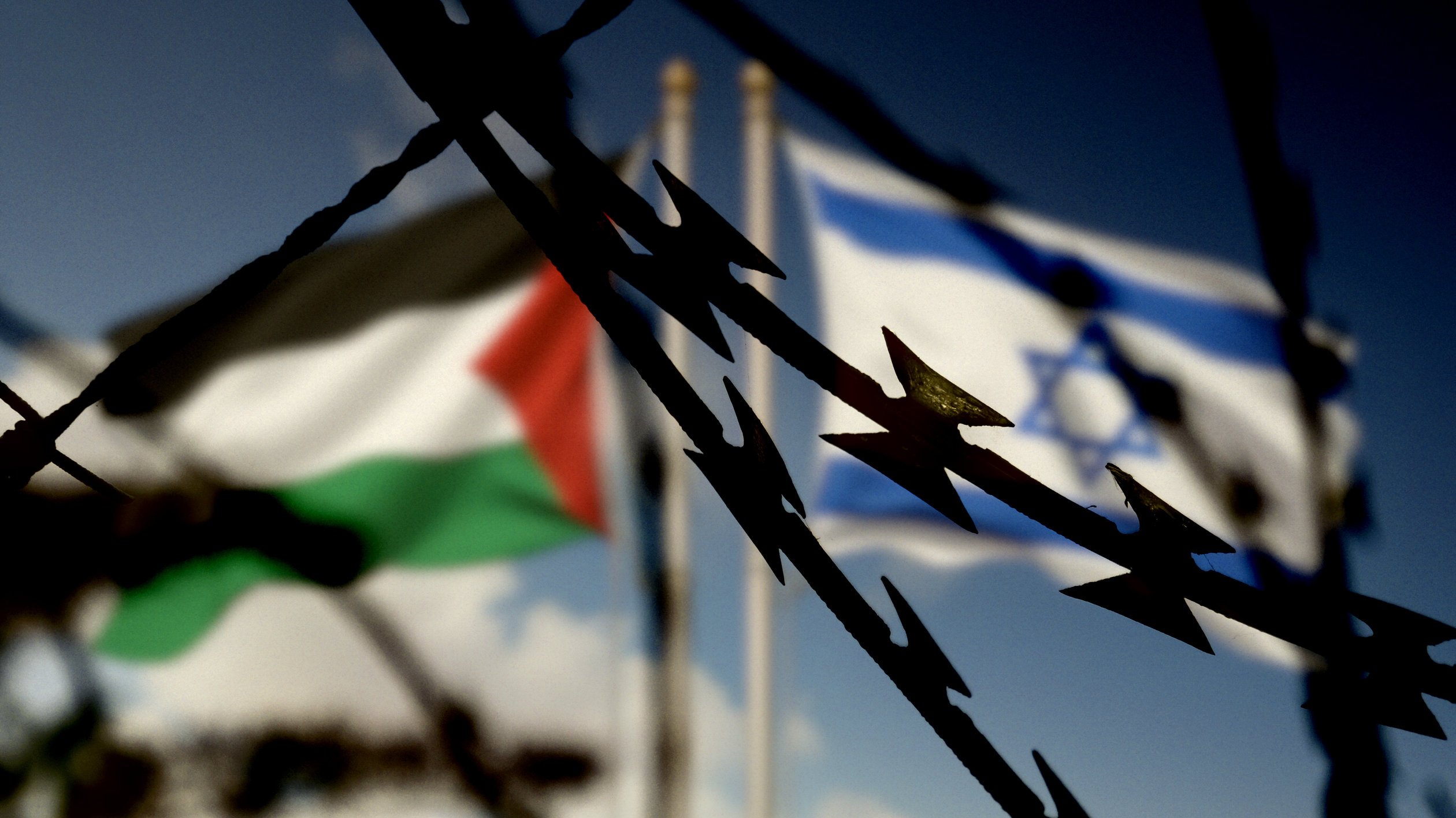 Flaggen von Israel und Palästina hinter dem Stacheldraht